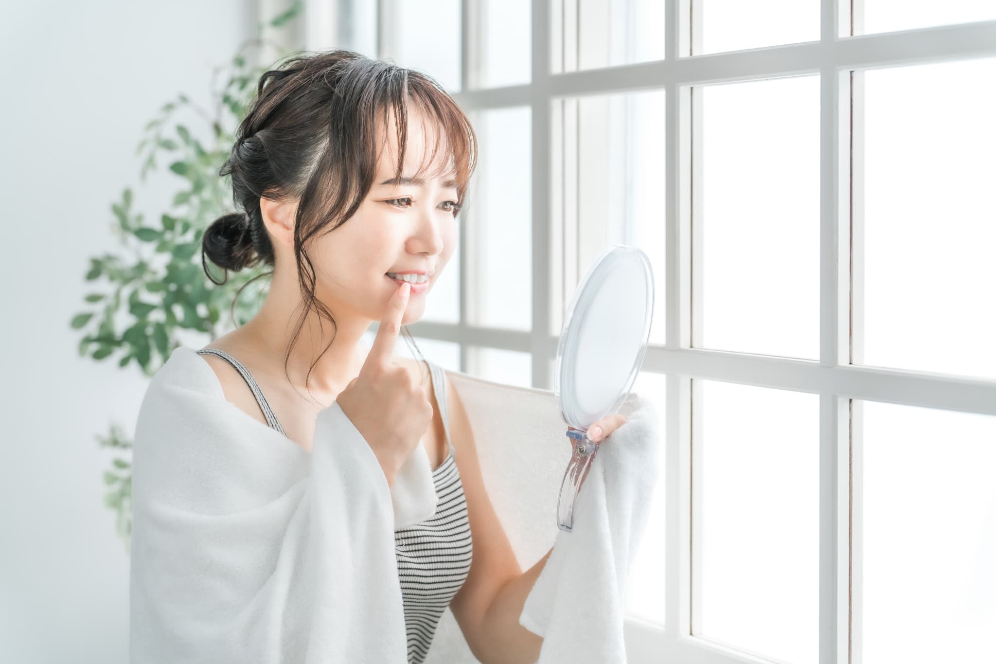 前歯の見た目が気になり鏡を見る女性