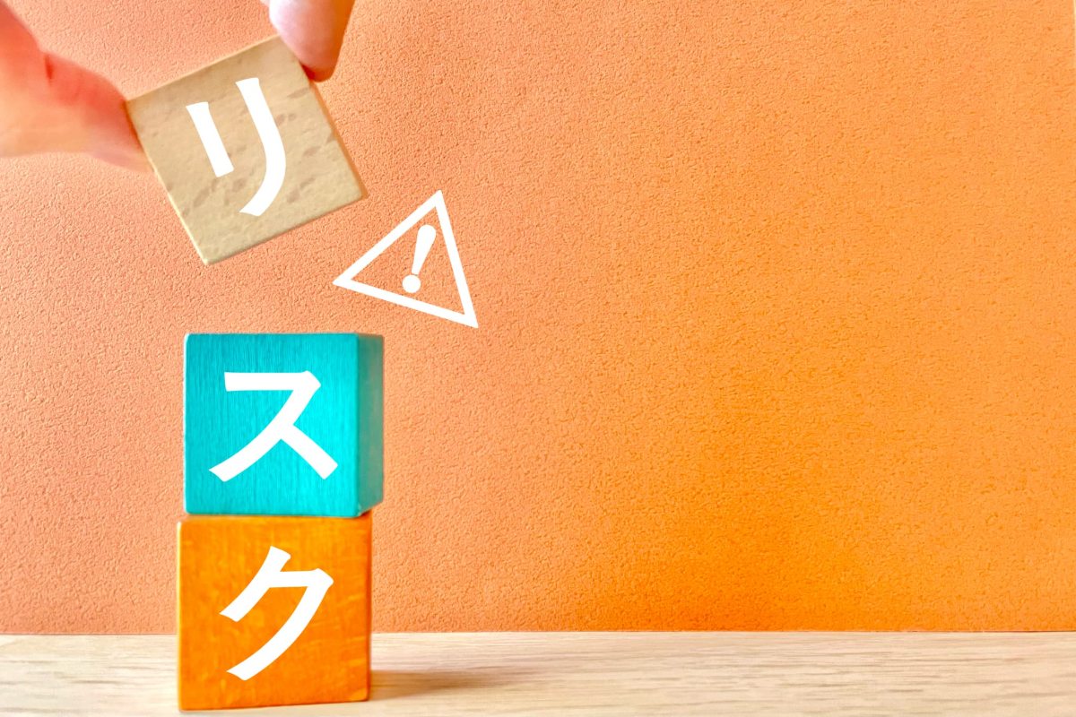 リスクと書かれたカラフルなブロックを積んでいる指とビックリマーク