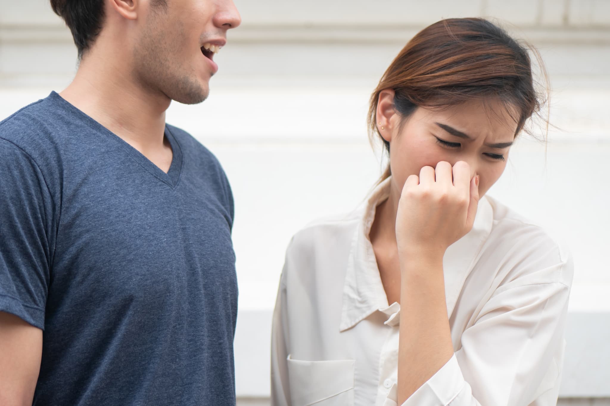歯周病で口臭がする男性に鼻をつまんで顔をそむける女性